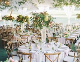 tented wedding reception with tall wedding centerpiece in glass vase including white hydrangea, pink proteas and greenery