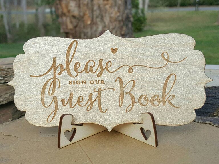 Wooden engraved sign with 'please sign our guest book' in cursive