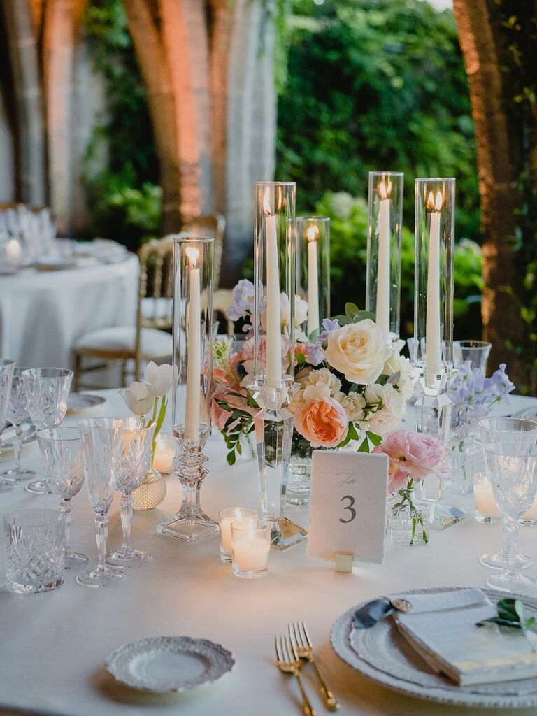 luxury wedding centerpiece with pastel flowers and white taper candles in glass vases