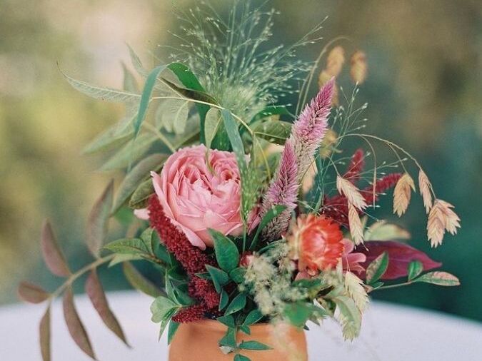 A petite flower arrangement with celosia in a clay vase