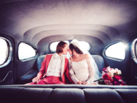 Couple toucjing noses sitting in back of limo on wedding day