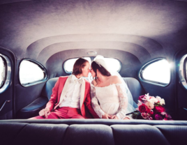 Couple toucjing noses sitting in back of limo on wedding day