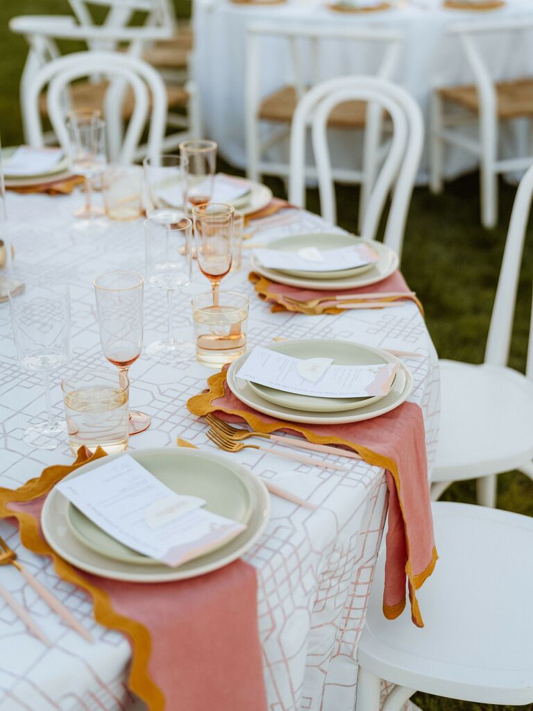 modern wedding tablescape with white patterned tablecloth and pink and orange napkins
