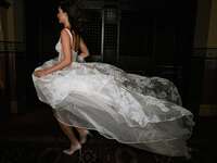 Model runs while a white floral wedding gown billows behind her. 