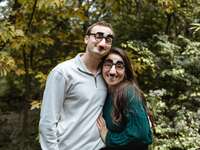 Couple poses for the camera wearing funny glasses. 