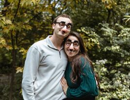 Couple poses for the camera wearing funny glasses. 