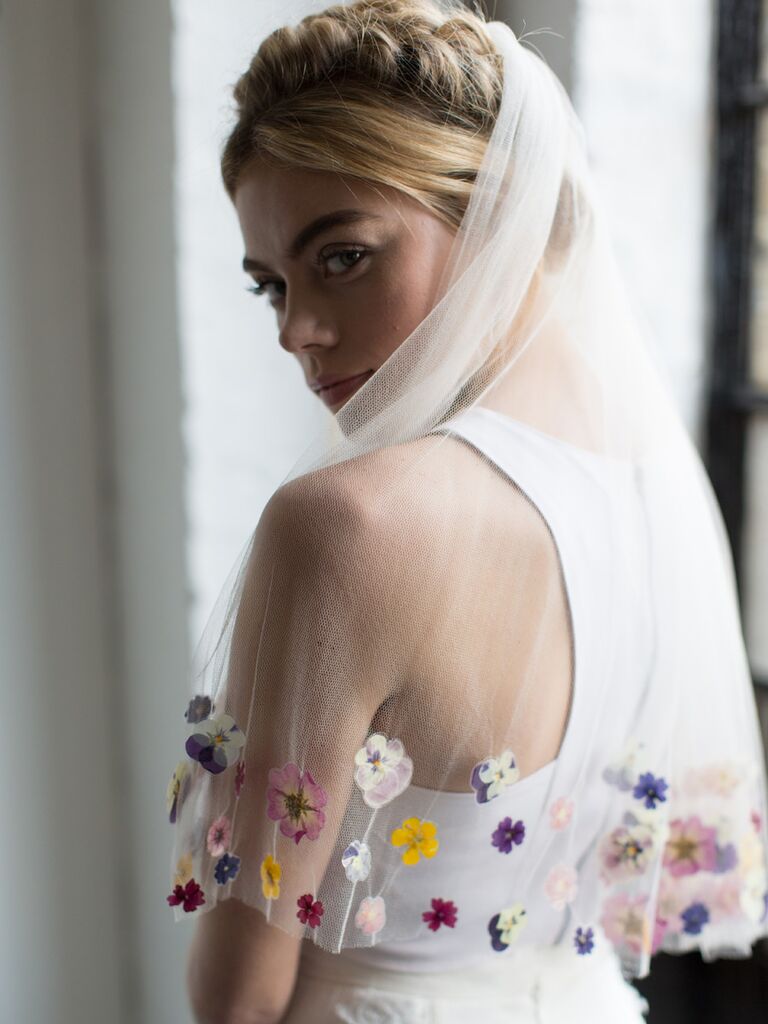 Model wears a beautiful sheer veil with flowers stitched on the trim. 