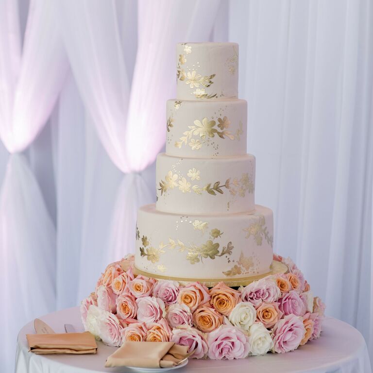 Gold-and-white wedding cake with fresh rose cake stand
