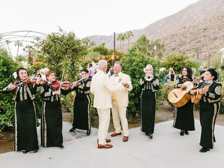 Grooms dancing to mariachi band at wedding reception