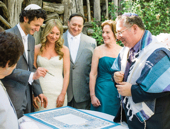 Bride and groom signing their ketubah at their wedding. 