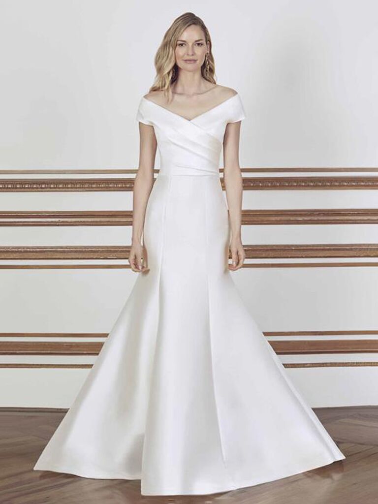 sareh nouri plain white off the shoulder wedding dress with v-neckline crisscross straps and form fitting pleated flowy skirt