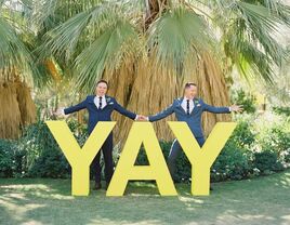 Couple holding hands beside YAY marquee sign