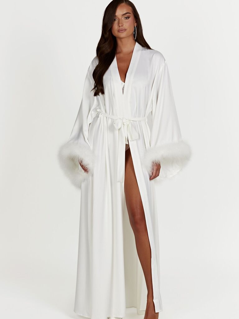 Model wearing a long satin robe in white with a chic feather trim