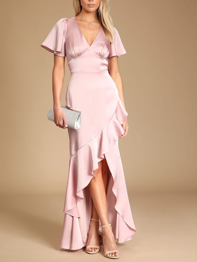 Model wearing a pink satin gown with sleeves and a v-neckline