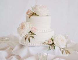 two tier simple wedding cake with white buttercream, ivory roses and blush rosebuds