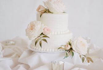 two tier simple wedding cake with white buttercream, ivory roses and blush rosebuds