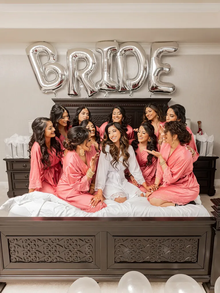 Bride and bridesmaids posing on bed before wedding