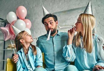 Family celebrating a birthday with party hats and balloons