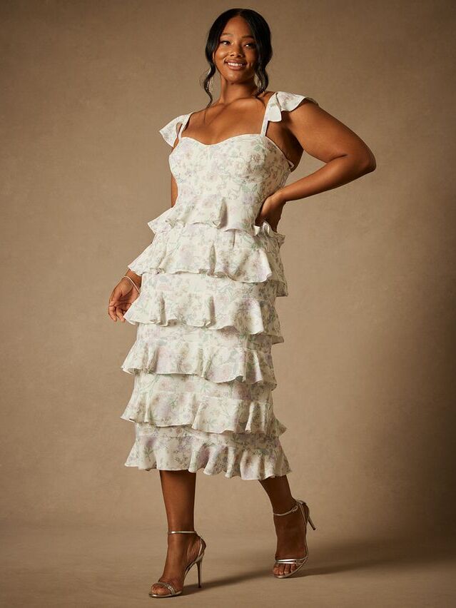 Model wears a white tiered dress with romantic ruffles. 