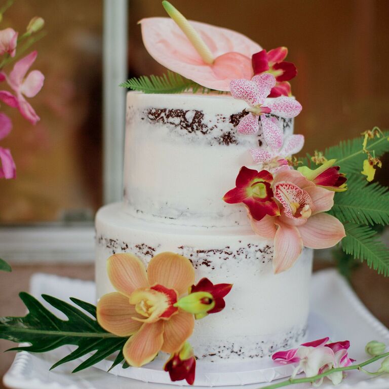 Semi-naked two-tier cake with tropical flower decorations
