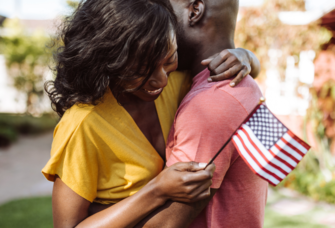 Couple hugging and holding small American flag on fourth of july
