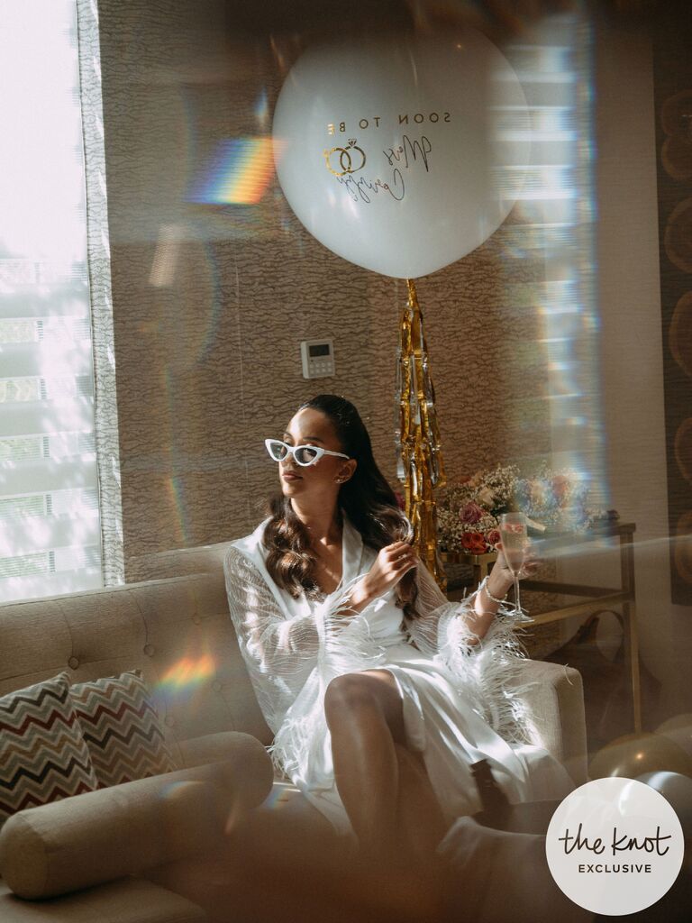 Erika Priscilla wearing sunglasses posing for bridal portrait with a balloon and champagne