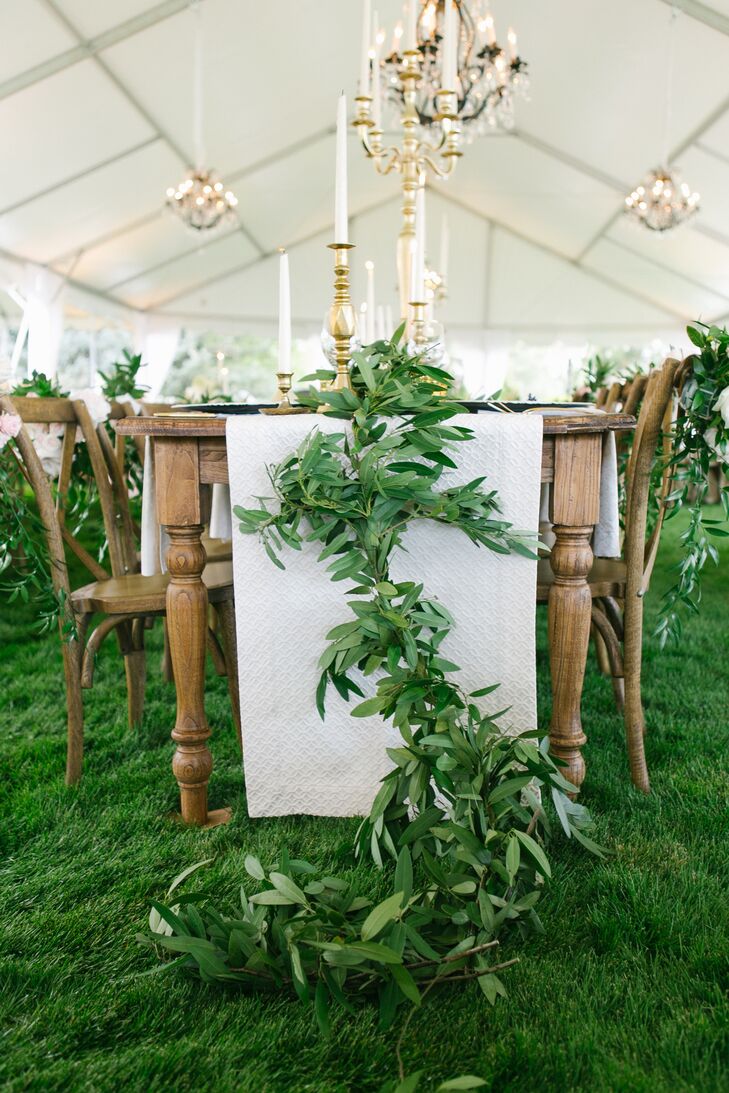Tented outdoor wedding reception with white table runners and garland