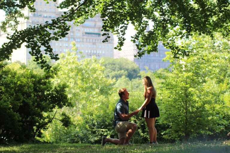 Once the idea of engagement began, Marshall began brainstorming and realized that no matter what, the element of surprise had to be executed to perfection. After going to the sounding board with several options, Payton's mother helped him pull it off without a hitch. Payton, her mom, and her sister were in NYC on a girl's trip. To Payton's knowledge, Marshall was at work until she got back from the trip. He got off work on a Friday morning, made his way to the airport, and was on a flight to NYC. He was able to connect with Payton's cousin who was going to photograph the proposal in Central Park. After some miscues and last minute changes, here comes Payton walking up a path not far from the “Friends” fountain in Central Park. As she approaches a tree, out steps Marshall, and the element of surprise had been achieved!