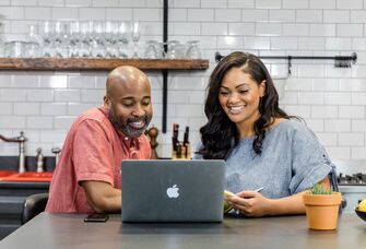 Engaged couple making wedding registry checklist on laptop