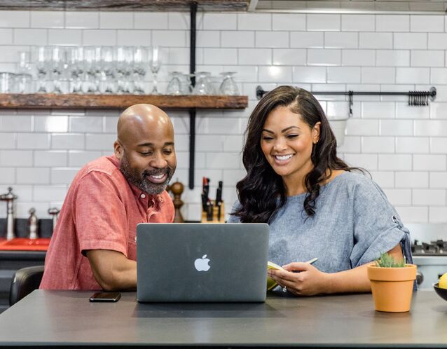 Engaged couple making wedding registry checklist on laptop