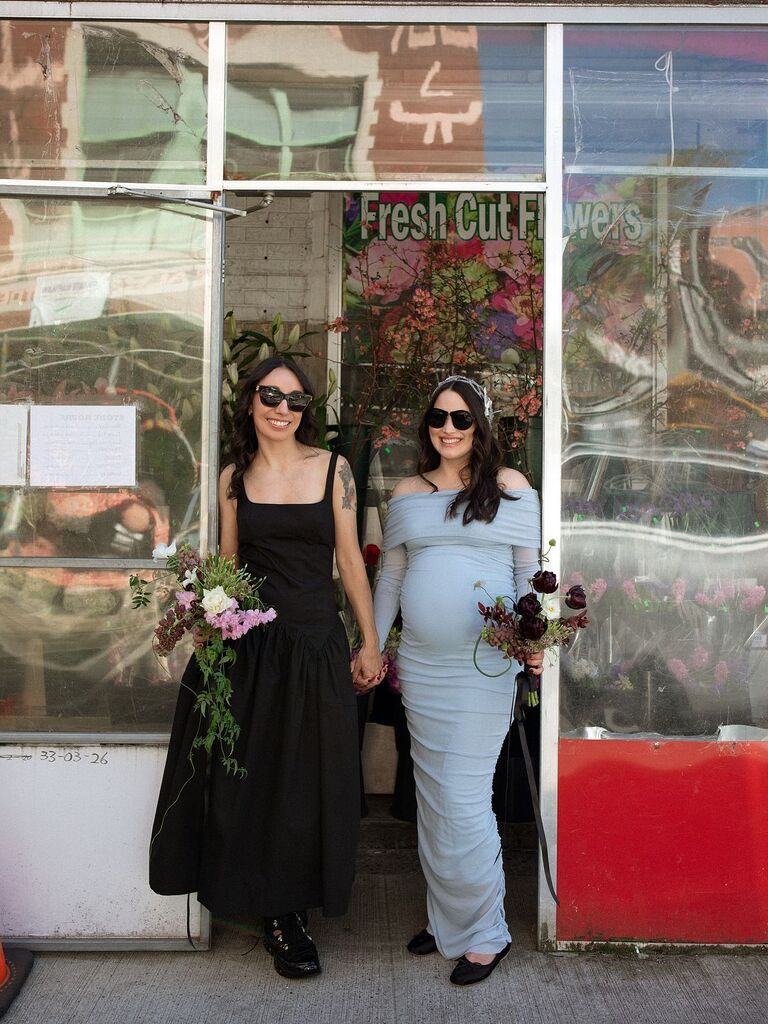 Two brides, one pregnant, holding hands
