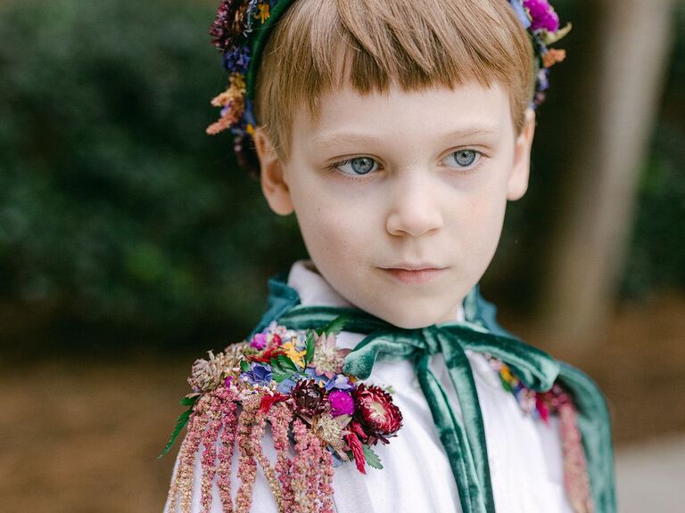 ring bearer wearing flower crown and cape with amaranthus