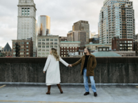 Couple's engagement photos on roof of parking garage with Boston skyline background