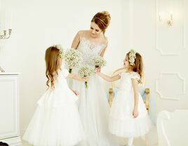 Two flower girls talking to the bride on her wedding day