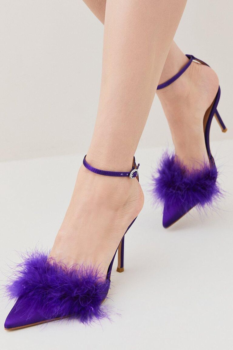 Deep purple high heels with an ankle strap and feathers on the toe. 