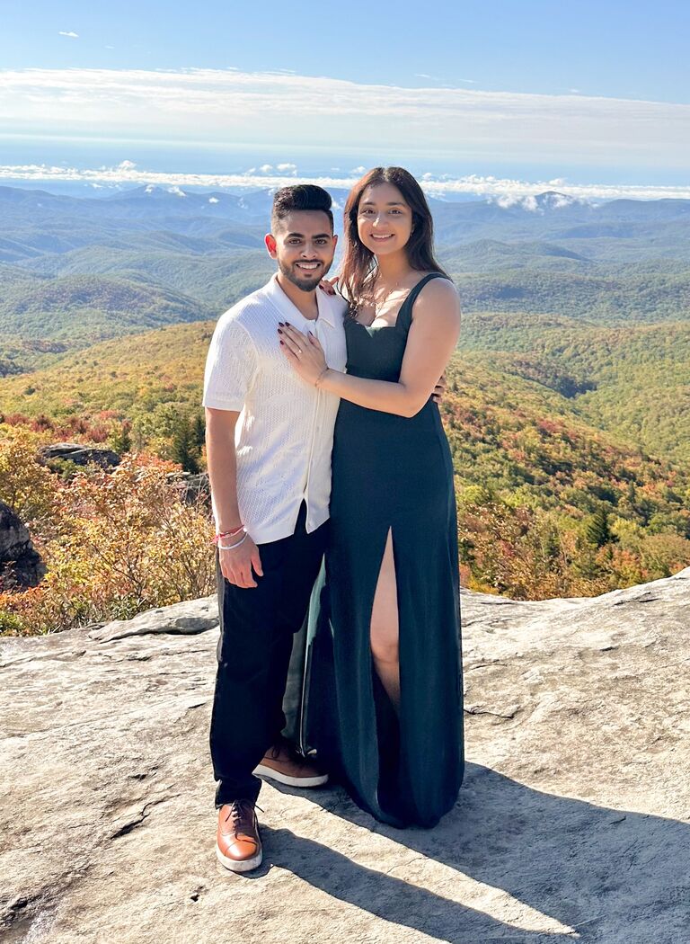 Then the BIG DAY October 12, 2023—a day we will never forget. Megha had always dreamed of a proposal on a mountain with a stunning view. She even had a special dress picked out for the occasion, though she had no idea her dream was about to come true that Thursday morning. At 5:30 AM, Keyur somehow convinced Megha to wear the dress by promising he’d buy her an even better one when the time came. She reluctantly put on the dress with her tennis shoes, completely unaware of what was about to unfold.

When we reached the top of the mountain, Keyur began setting up his camera gear, something he always did during our adventures. He asked Megha to stand on a specific rock so he could center the lens—a request she didn’t think twice about since she was used to being his focus point for photos. As she stood there, taking in the breathtaking view with her back turned, Megha suddenly heard footsteps behind her. Then Keyur softly said her name.

When Megha turned around, she found Keyur down on one knee, holding the ring of her dreams.

In that magical moment, surrounded by the mountains and with the sun rising in the background, Keyur asked Megha the question she had unknowingly been waiting for. And her answer, without hesitation, was “yes.”