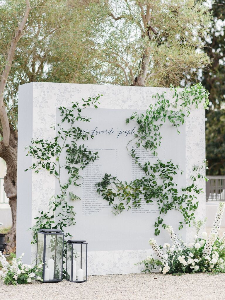 Large white seating chart display with greenery decorations