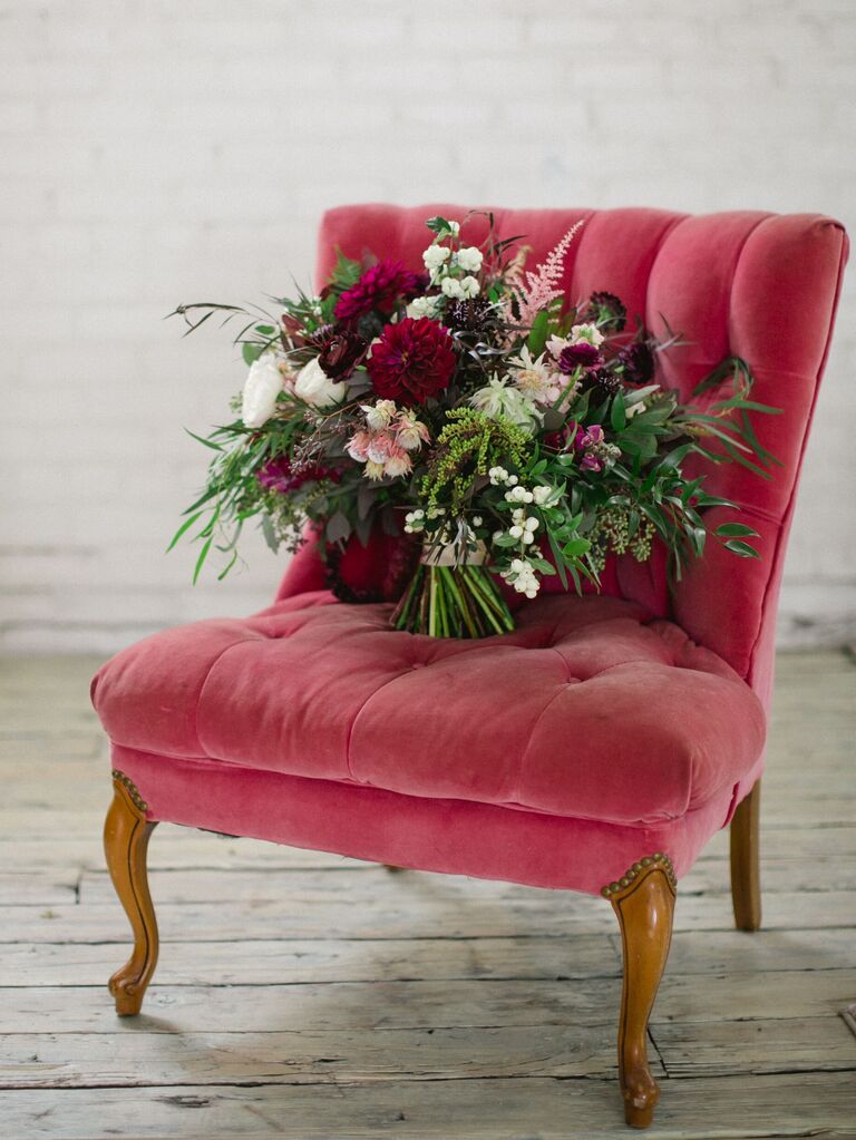 winter bouquet with red and pink flowers sitting on red velvet chair