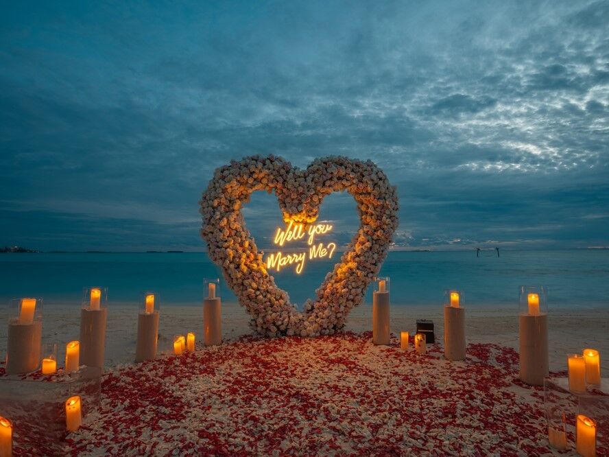 Romantic beach proposal with rose petals and candles