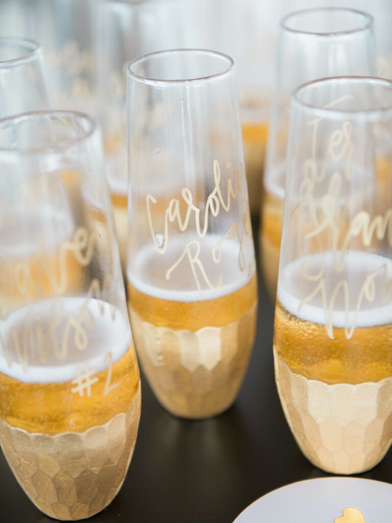 wedding champagne flute escort cards with guest names written in gold calligraphy