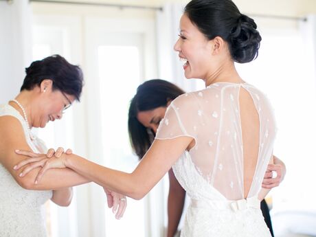Bride with mother trying on wedding dress