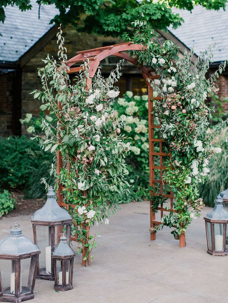 Rustic floral arch at barn wedding entrance with distressed lanterns