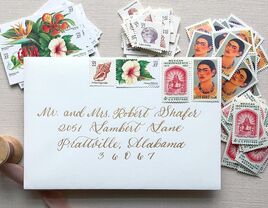 Seashell, white hibiscus, red Mexican independence and Frida Kahlo designs on white envelope with gold calligraphy