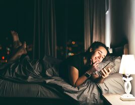 woman looking at phone while in bed