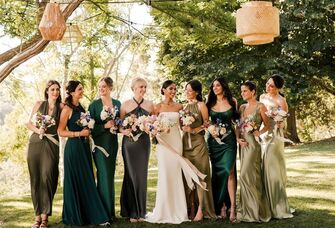 Bride with bridesmaids smiling while linking arms