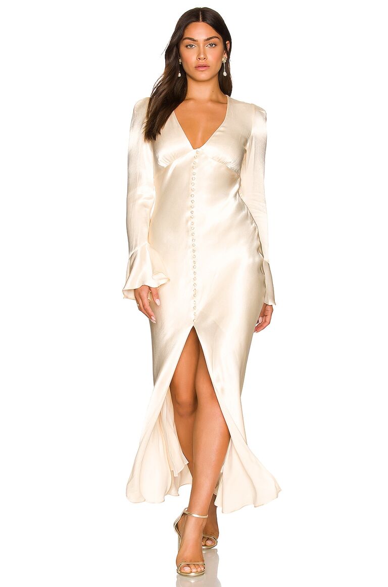 Model wears a cream colored silk dress with buttons down the front. 