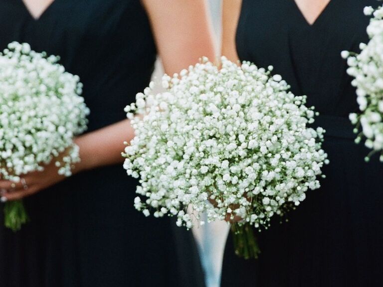 bridesmaids in black dresses holding baby's breath bouquets