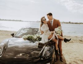 Couple sitting on top of a wedding car and posing for a picture