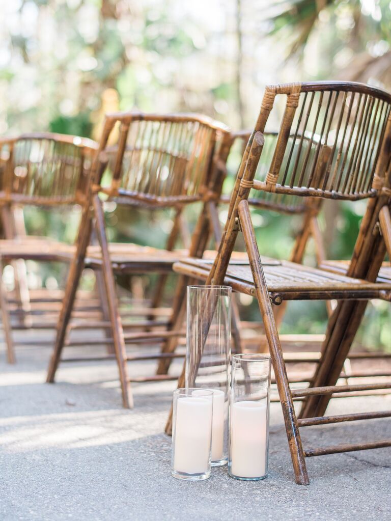 rows of bamboo folding chairs at wedding ceremony with candles in assorted glass vases