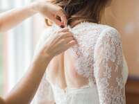 Bride putting on wedding dress